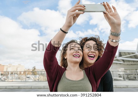 Two beautiful women taking selfiein the street. Friendship concept.
