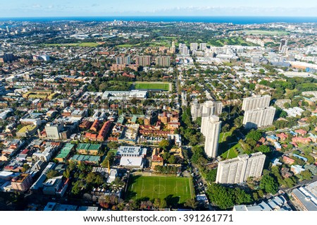 Aerial photo of typical Sydney neighbourhood suburb. Residential buildings with office skyscrapers among green parks and sport fields - modern urban infrastructure 