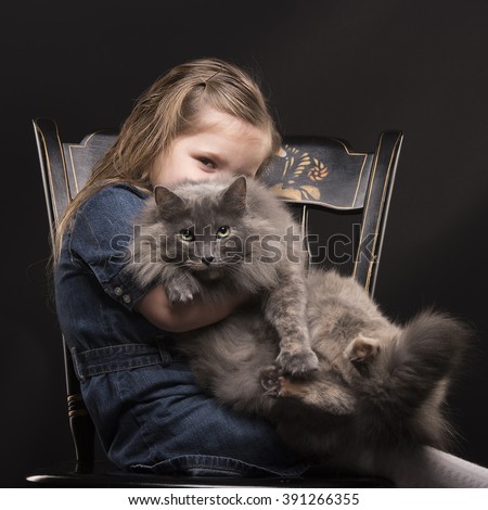 Young girl sitting on chair with a cat on her lap and looking with one eye