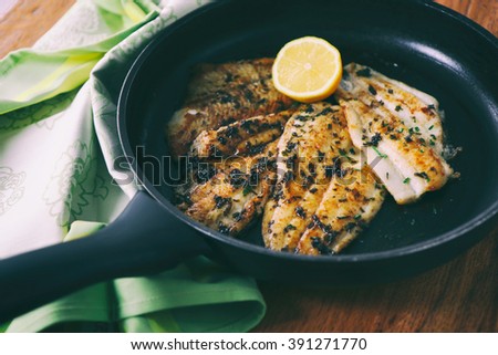 Flounder fillet roasted in a skillet with herbs and lemon butter 