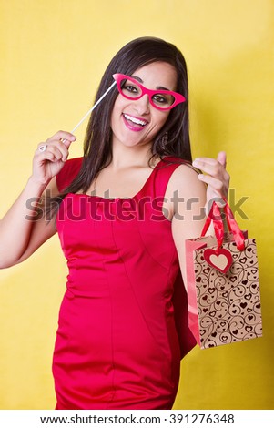 Happy woman in red dress with red glasses and gift