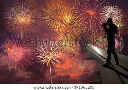 silhouette of photographer taking photo on airplane wing which can see Fantastic festive colorful fireworks, Challenge and success business concept