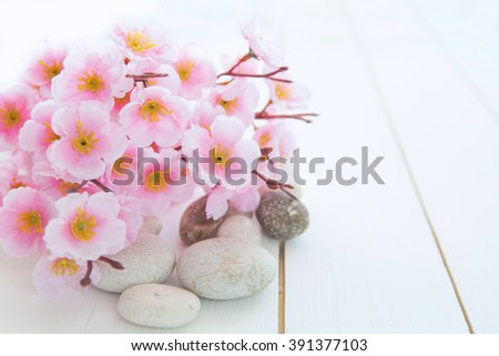 Spa stones with pink sakura flowers on white wood table