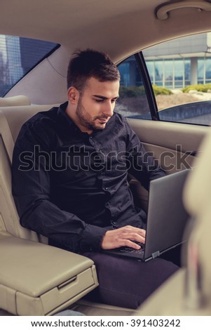 Young bearded businessman with laptop in the car.