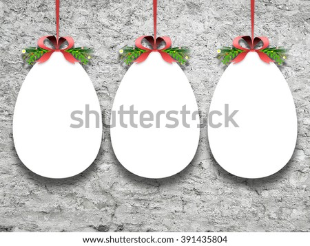 Close-up of three hanged blank Easter egg frames with ribbon against rough wall background