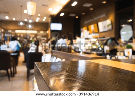 Empty wood table top with blur of people in coffee shop/cafe restaurant background.