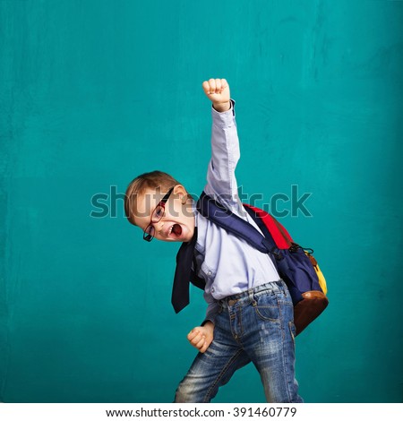 Cheerful smiling little boy with big backpack jumping and having fun against blue wall. Looking at camera. School concept. Back to School Royalty-Free Stock Photo #391460779