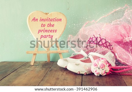 Small girls party outfit: white shoes, crown and wand flowers on wooden table. bridesmaid or fairy costume. vintage filtered

