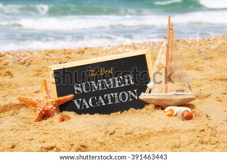 starfish and sailboat next to chalkboard with phrase: THE BEST SUMMER VACATION, on sea sand and ocean horizon. selective focus
