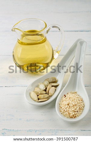 Pumpkin and sesame seeds with oil on wooden table