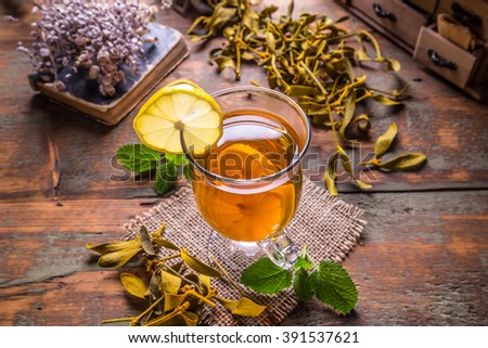 Cup of fresh herbal tea on rustic background