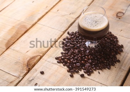 Snifter glass with coffee stout surrounded by roasted coffee beans over a grunge wooden background Royalty-Free Stock Photo #391549273