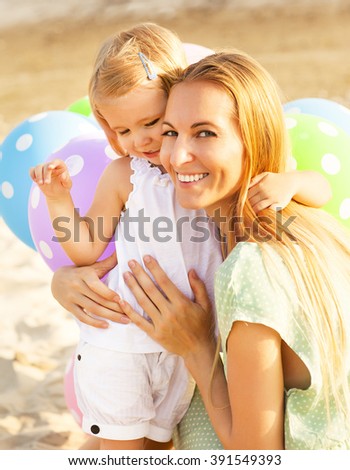 Happy woman and her little daughters with ballons outdoors. Mother day or Birthday concept