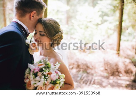 Bride and groom in a park kissing.couple newlyweds bride and groom at a wedding in nature green forest are kissing photo portrait.Wedding Couple Royalty-Free Stock Photo #391553968