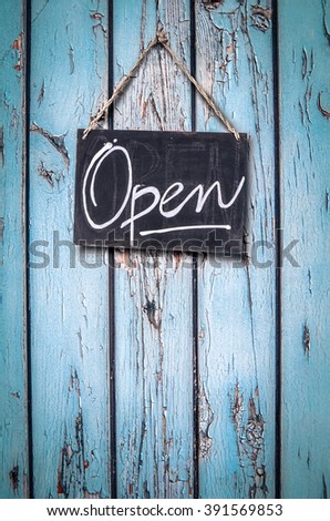 Rustic Hanging Open Sign On A Door With Peeling Blue Paint