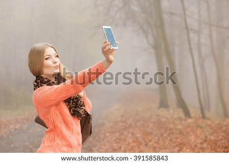 Happy fashion woman in fall autumn park taking selfie self photo picture. Pretty joyful young girl in sweater pullover photographing.