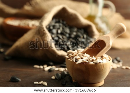 Sunflower seeds in bag and bowl on wooden table background, closeup