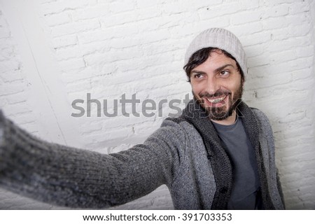 young attractive man in casual clothes beanie hipster style holding off screen mobile phone shooting self portrait photo selfie or recording video in internet blog and blogger concept
