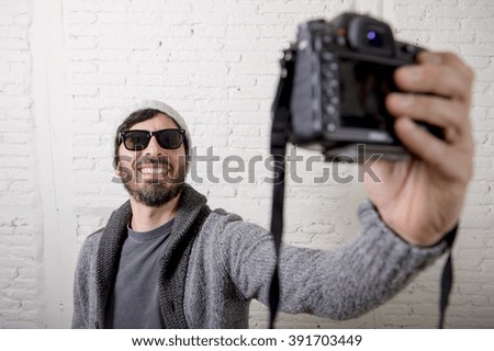 young attractive man wearing casual clothes sunglasses in hipster style modern look holding photo camera shooting self portrait selfie picture or recording video in internet blog and blogger concept