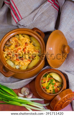 Two clay pots with baked potato and green onion