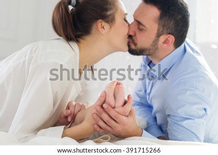 Happy parents are holding childs foots