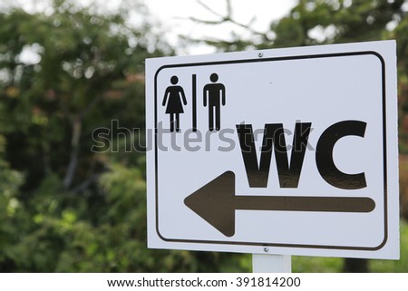 Toilet sign for man and female on white table outside in field