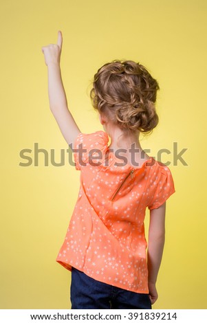 teen girl pointing at copy space on yellow background
