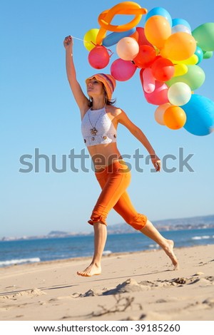 young woman with colorful balloons on the beach