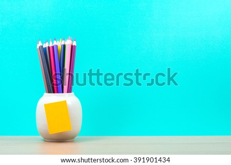 colour pencils in jar on table and green background