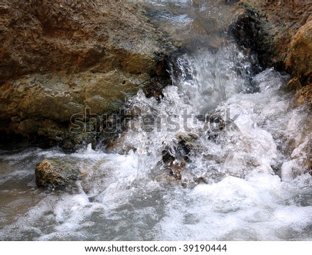 Motion picture of small waterfall between two rocks. Clean, cool water is  running through stones.