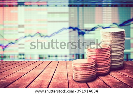 coin stack on old wooden floor with blur image of graph stock market background