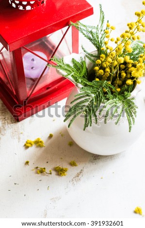 Bright yellow mimosa flowers in a vase on old rustic wooden table