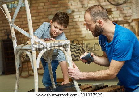 Father and son tinkering at home, renewing chair, polishing.
