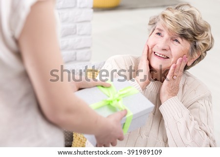 Cropped picture of a young woman giving a present to her suprised grandmother