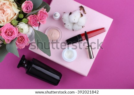 Beautiful make up bag with cosmetics and flowers on pink background