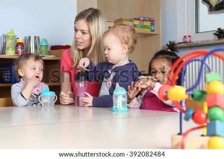 Some Kindergarten or nursery kids on a table drinking and playing  Royalty-Free Stock Photo #392082484