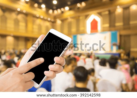 woman use mobile phone and blurred image of people in the hall in the school event