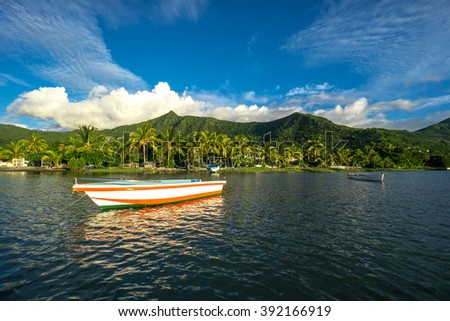 Fishing boats on the background of incredible golden sunset, clouds and high mountains. Mauritius Island, Indian Ocean