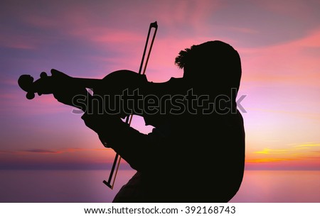 Silhouette of Violinist under the cloudy sky and near the lonx exposed sea via nd filter with purple filter applied