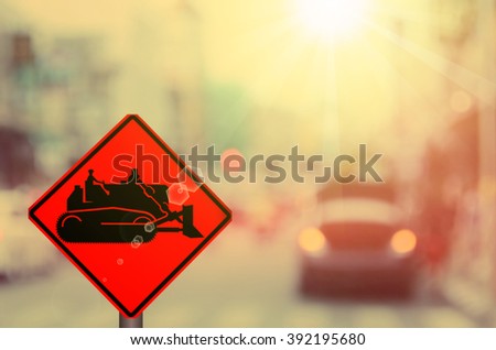 Construction tractor sign on blur traffic road abstract background.Retro color style.