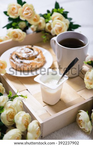 good morning - breakfast with sweet bun, yoghurt and tea on wooden tray
