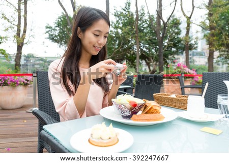 Young woman taking photo on her breakfast in outdoor cafe