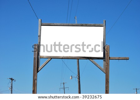 A photograph of a blank white wood sign frame against a blue sky background.