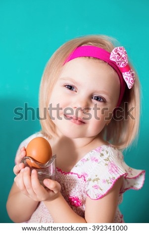 portrait of a little blond girl four years shows the Easter egg theme, smile gentleness spring, blue-green background