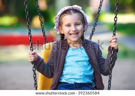 Child playing on playground. Happy little girl on a swing. Shallow depth of field. Selective focus.