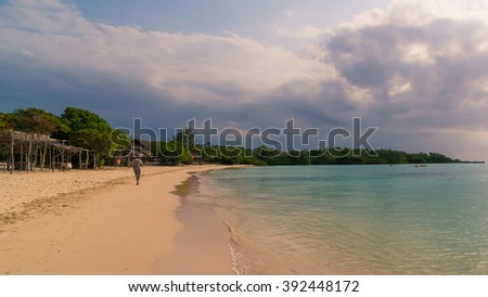 In the picture a man walking alone on a beautiful beach in Zanzibar in the evening. Republic of Tanzania.