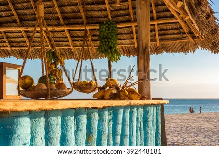 In the picture beach bar in Nungwi ( Zanzibar ) at sunset , with exposed coconut , banana and tropical fruit .This bar is made with cane bamboo,wooden and straw rope.