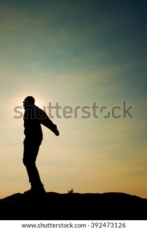 Man ready to jump. Adult crazy man is jumping on colorful sky background.Silhouette of man and beautiful sunset sky. Vintage effect