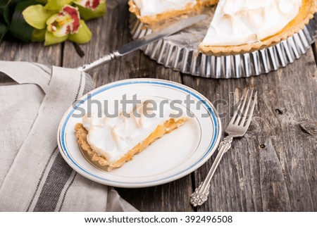 Piece of lemon meringue pie served on white plate on wooden background