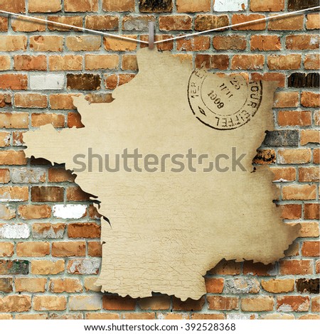 Close-up of one hanged vintage France shape old postcard with peg against weathered brick wall background